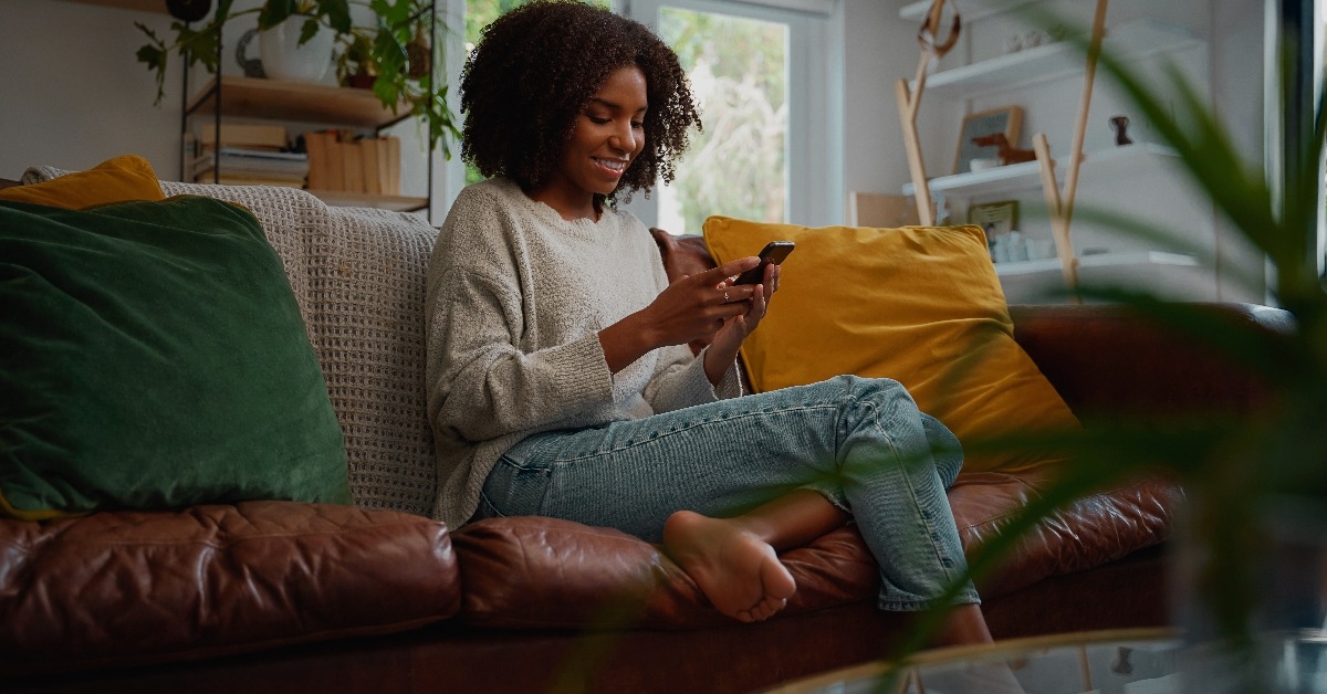 woman using mobile phone while sitting a couch at home