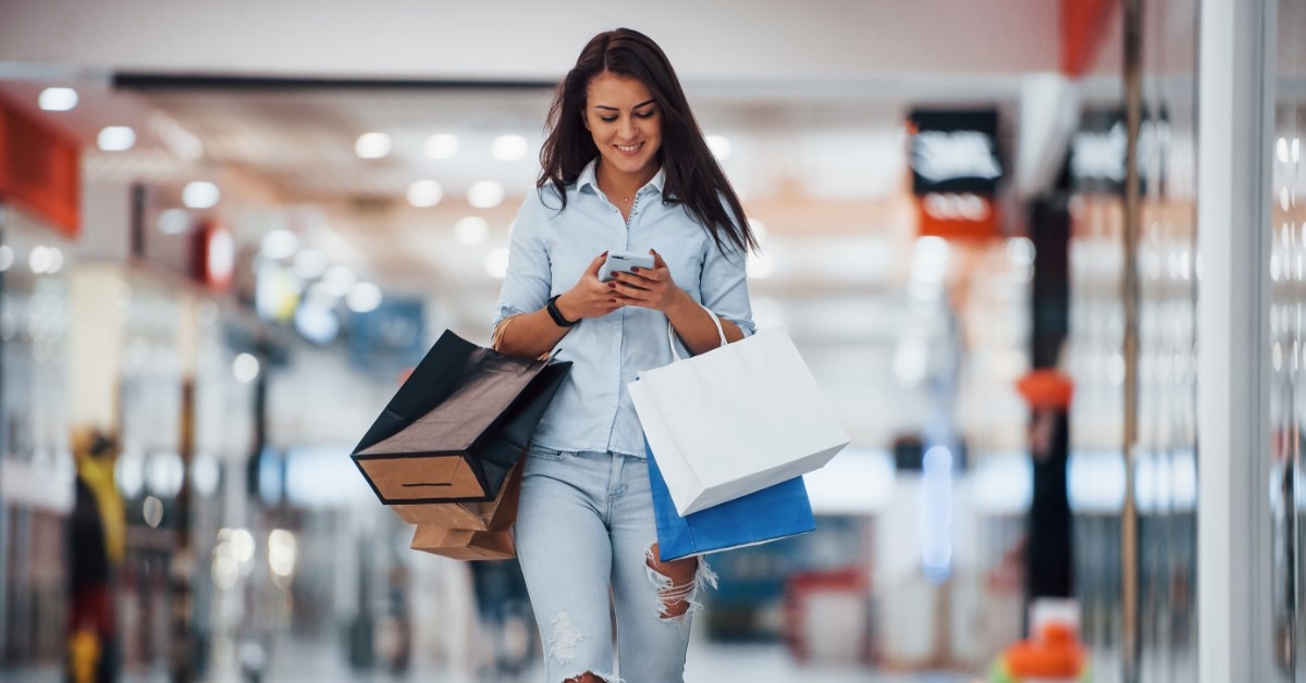 happy woman with lots of shopping bags using smartphone
