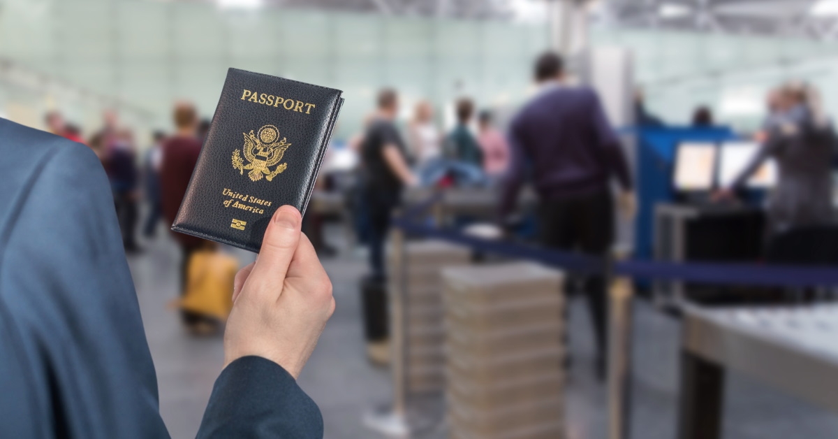 man in a blue suit holding passport and waiting for his turn at airport