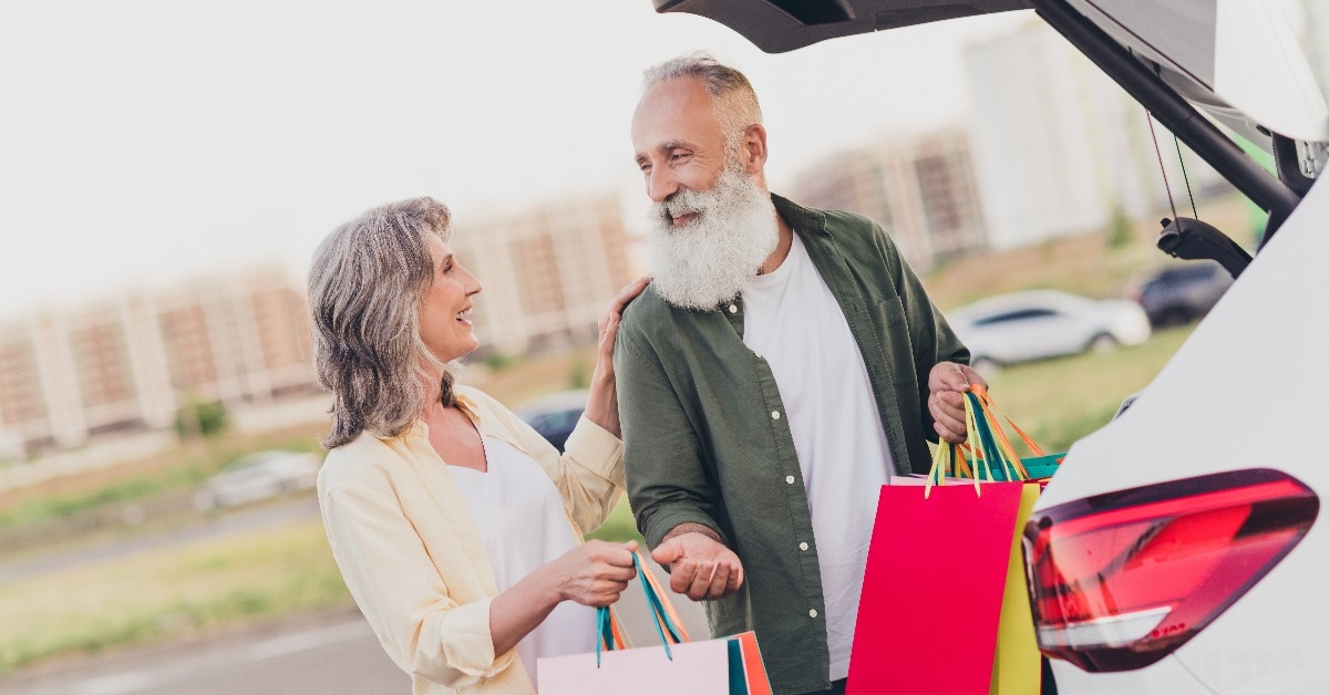 old couple shopper hold bags car outside outdoors in urban city