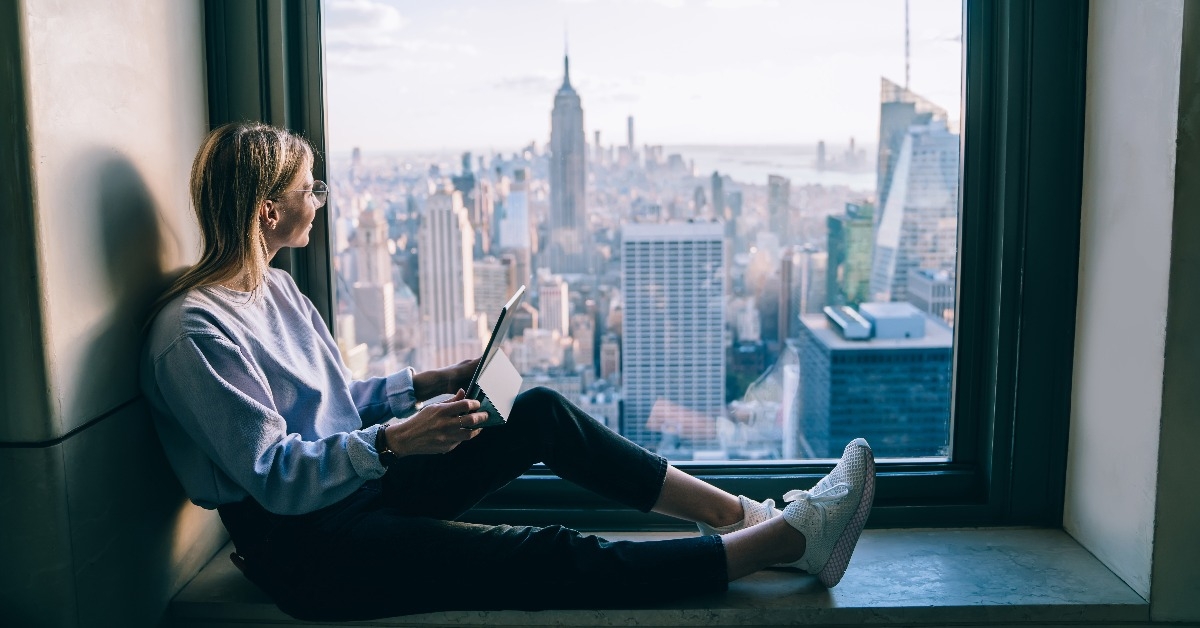 female tourist enjoying scenic views from hotel window 