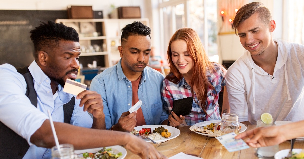 happy friends with money paying bill at restaurant