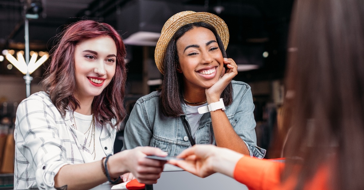 multicultural young women shopping and paying with credit card in boutique