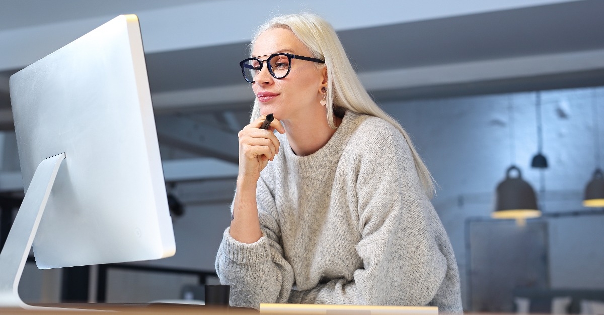 woman wearing eyeglasses sitting in front of a computer monitor