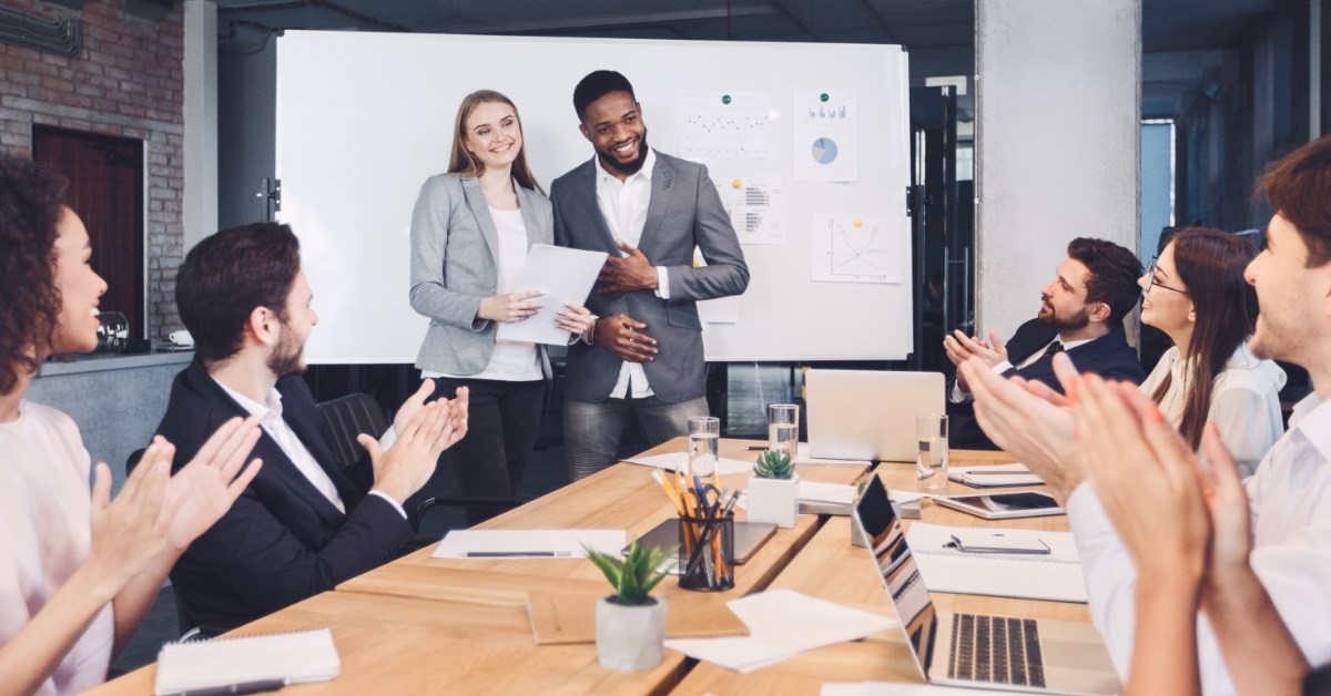 employees in an office applauding a man and woman