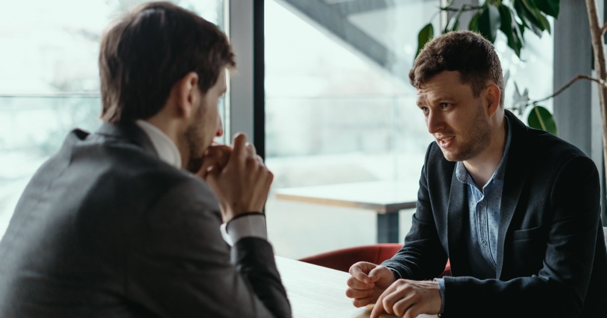 two businessmen sitting in front of each other discussing ideas