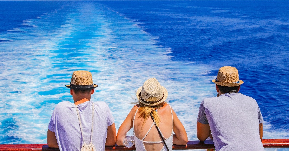 tourists with a straw hat stand on the deck of a cruise ship