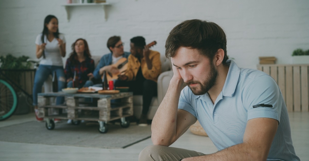guy feels upset and isolated while his friends are celebrating party at home