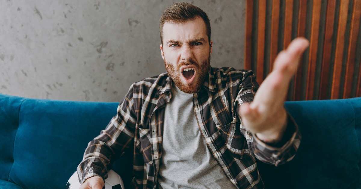 man in brown shirt holds remote controller