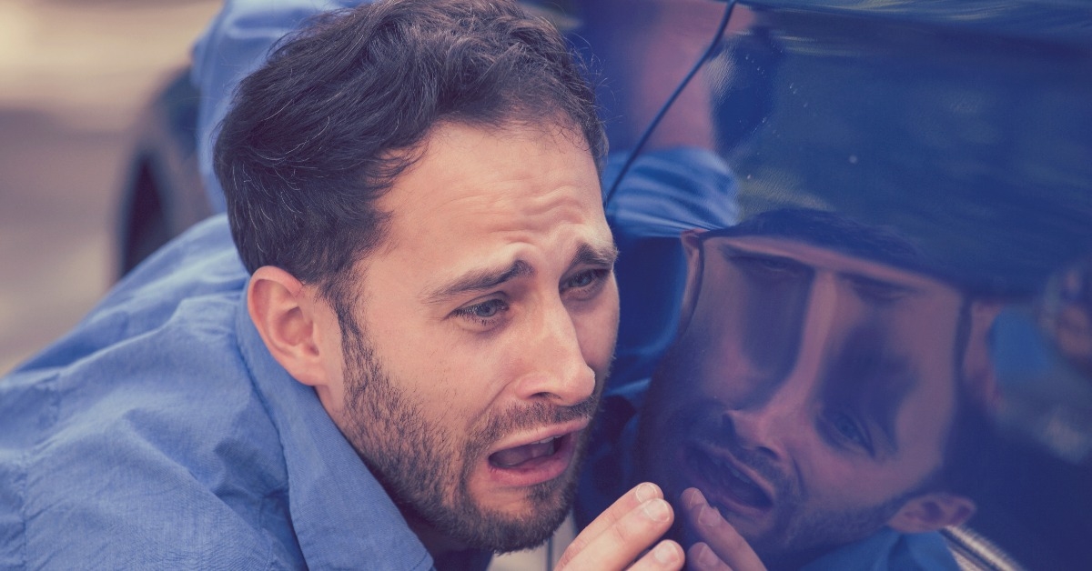 man looking at scratches and dents on his car