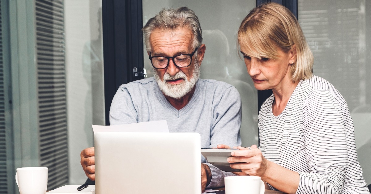 senior couple reading documents and calculating bills to pay