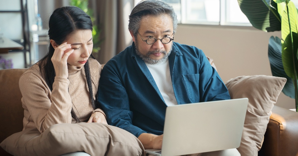 stressed couple calculate bills tax on the laptop