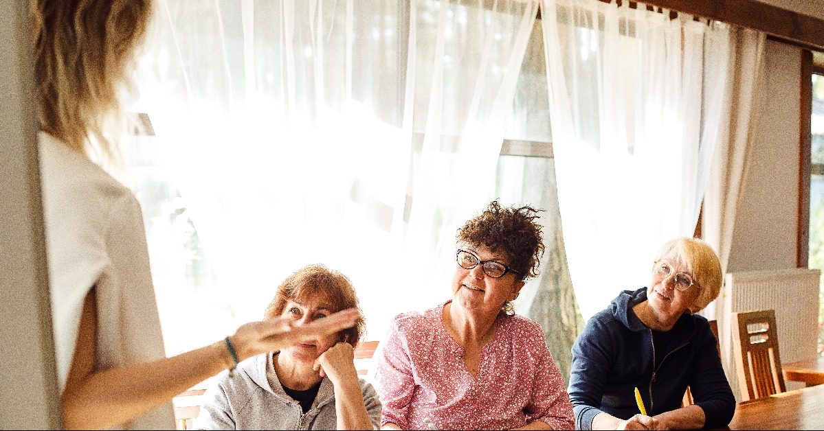smiling elderly women sitting at wooden desk