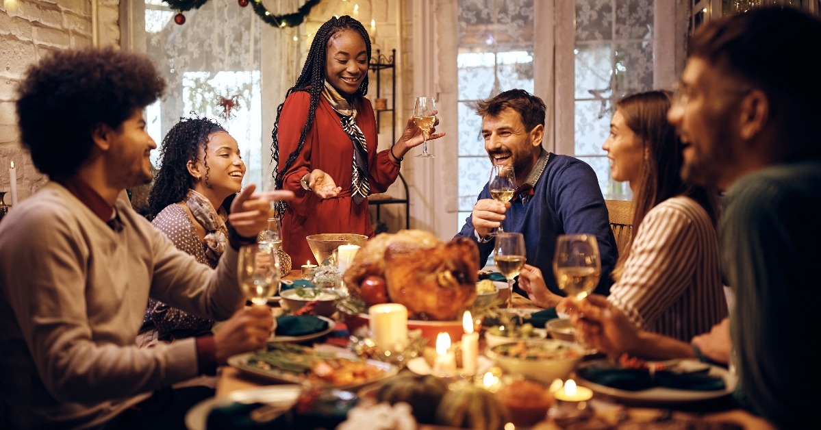 woman holding toast during Thanksgiving meal with friends at dining table