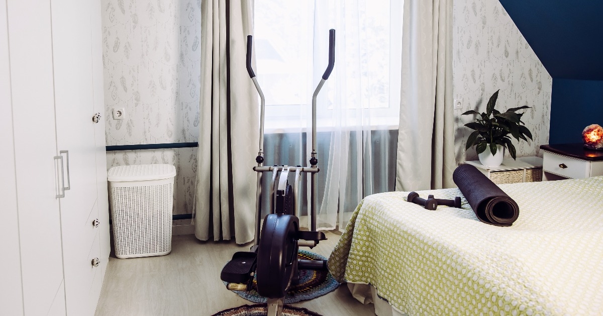 elliptical trainer weights yoga mat at home gym located in bedroom