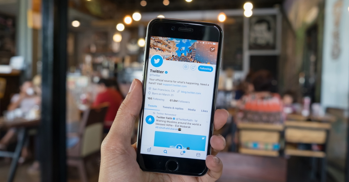 man using smartphone and surfing on twitter at a cafe