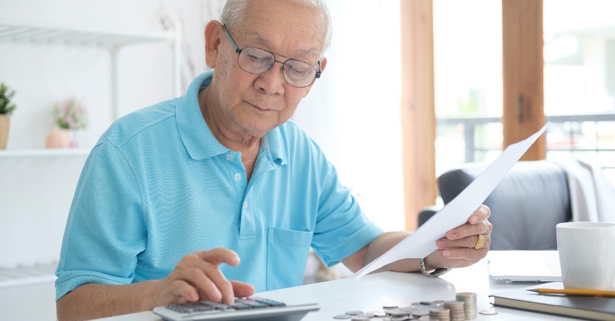 man sitting at table near utility bill and calculating expenses