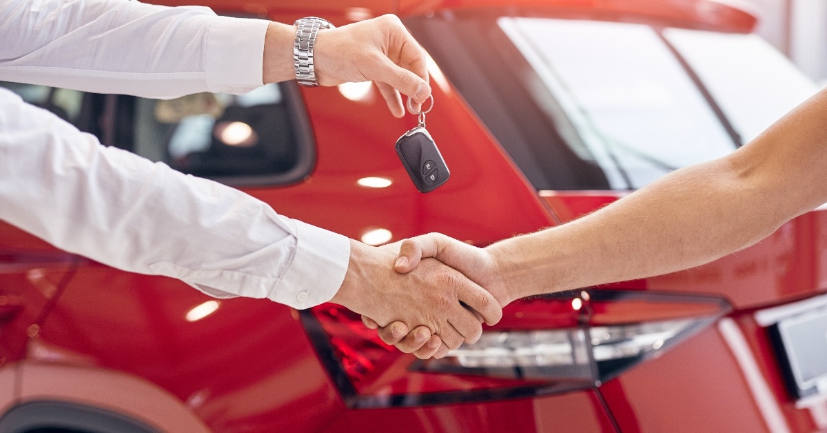 dealer with car keys shaking hand of client