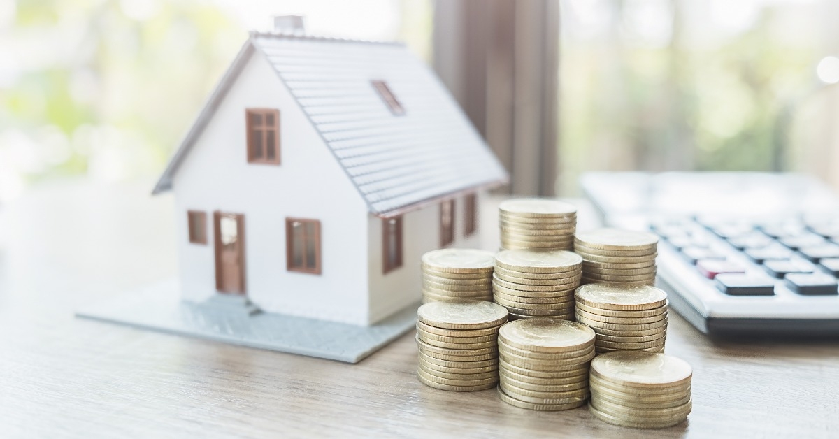 stack coins and house model on table