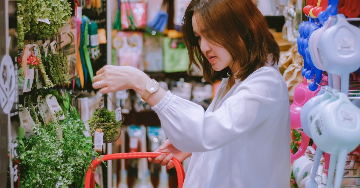 woman picking up artificial green plant for home decoration at retail shop