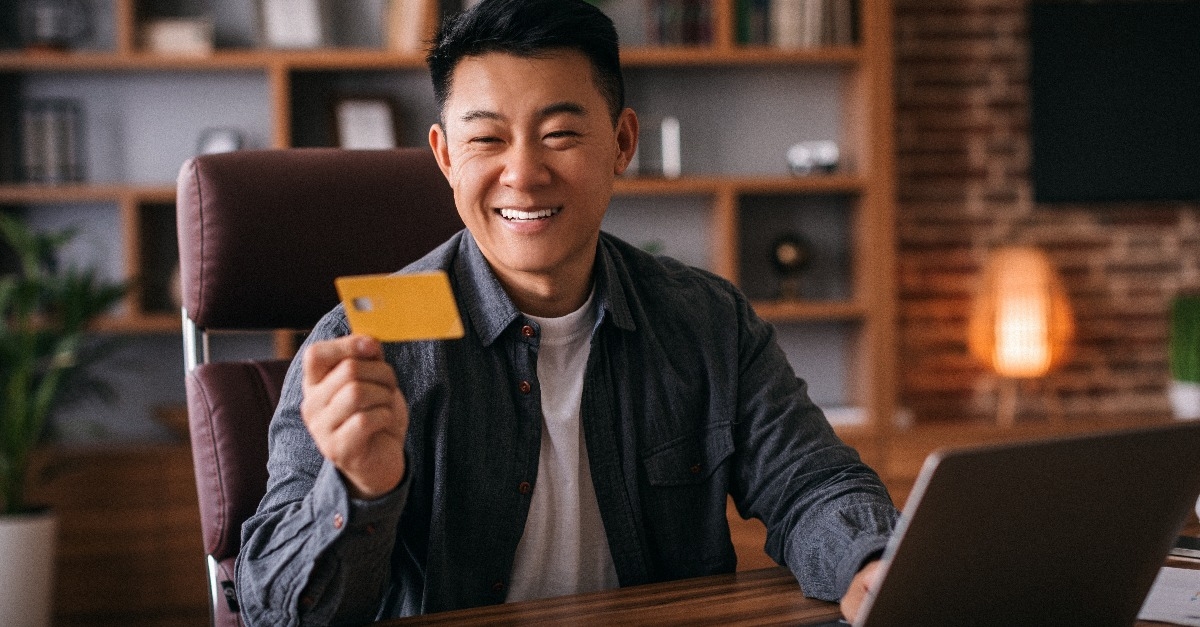 man at table with laptop use credit card 