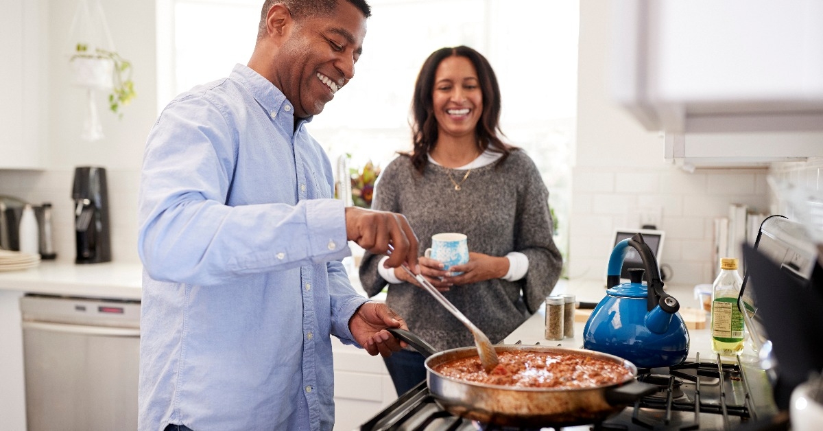 man standing in the kitchen cooking with his partner