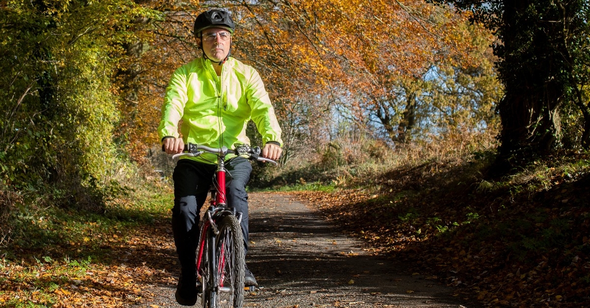 mature man cycling along autumn country road