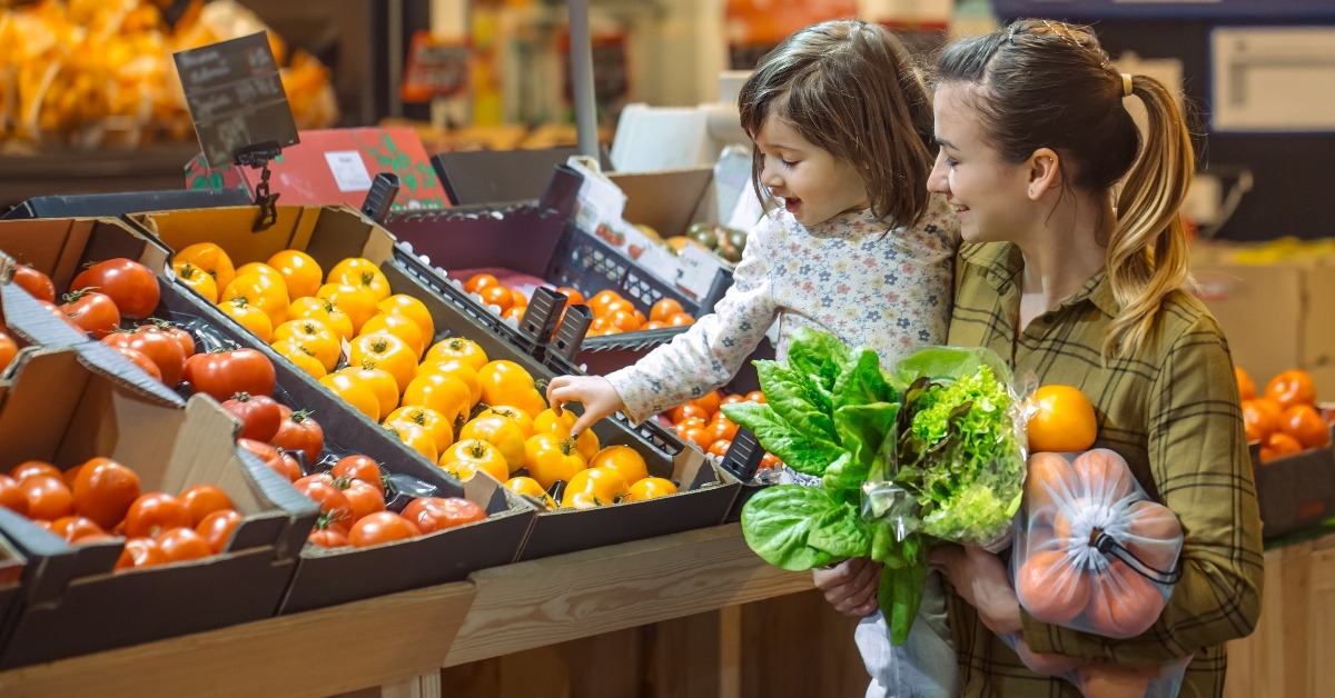 young mom and her little daughter buying in the supermarket