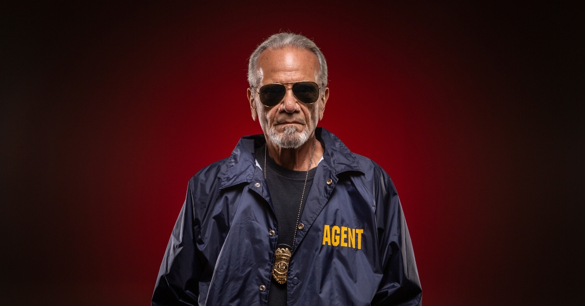 detective wearing badge around his neck and sunglasses