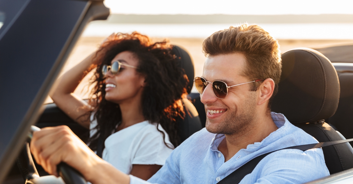 multiethnic couple riding in a convertible