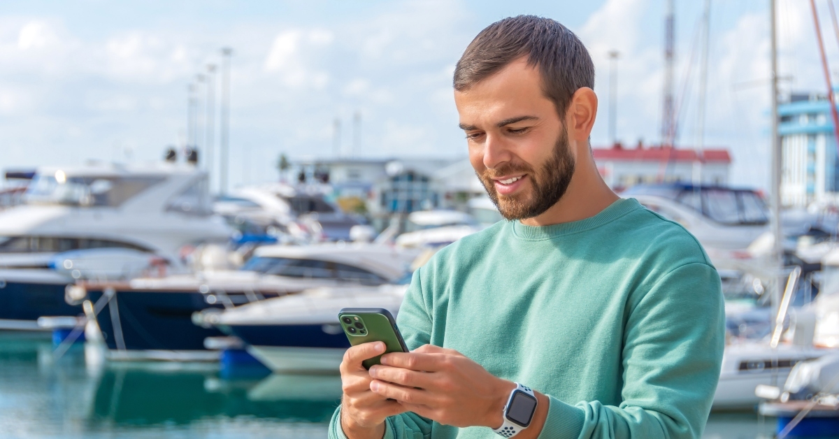 man smiling in a green sweater while texting in a smartphone messenger