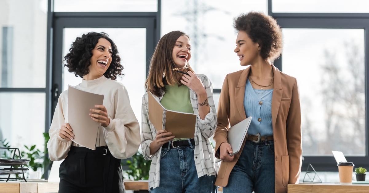 multicultural businesswomen holding laptop and documents in office