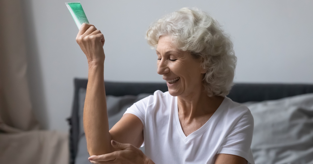 senior woman applying moisturizing cream on elbows