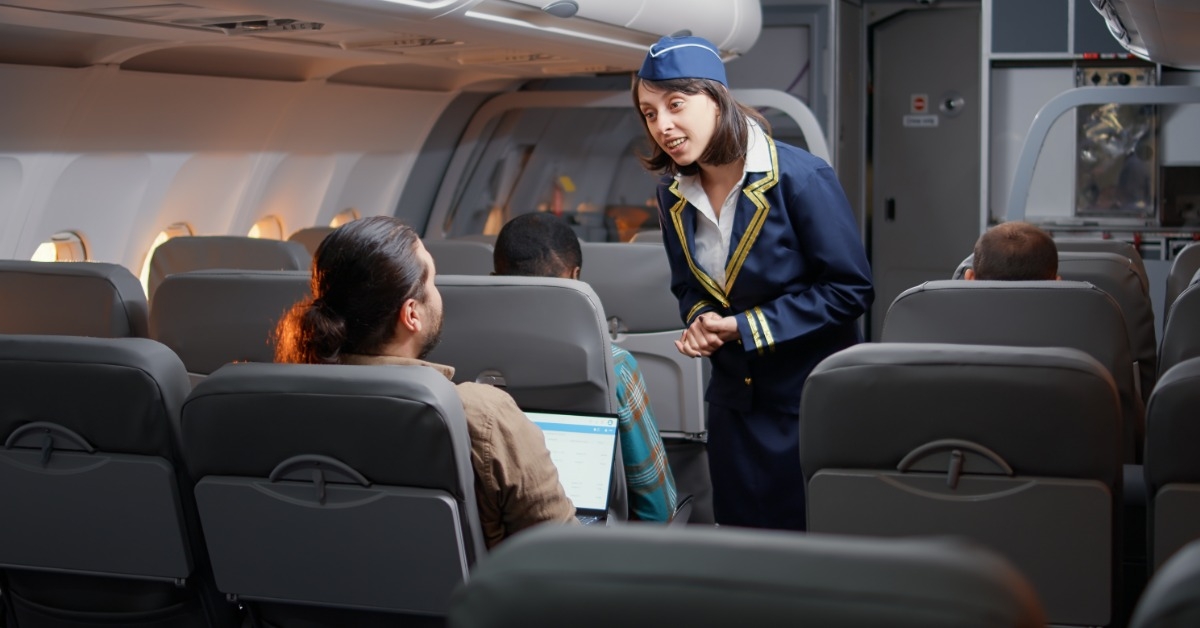 young stewardess talking to man using laptop