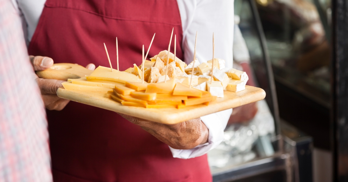 salesman holding cutting board with assorted cheese
