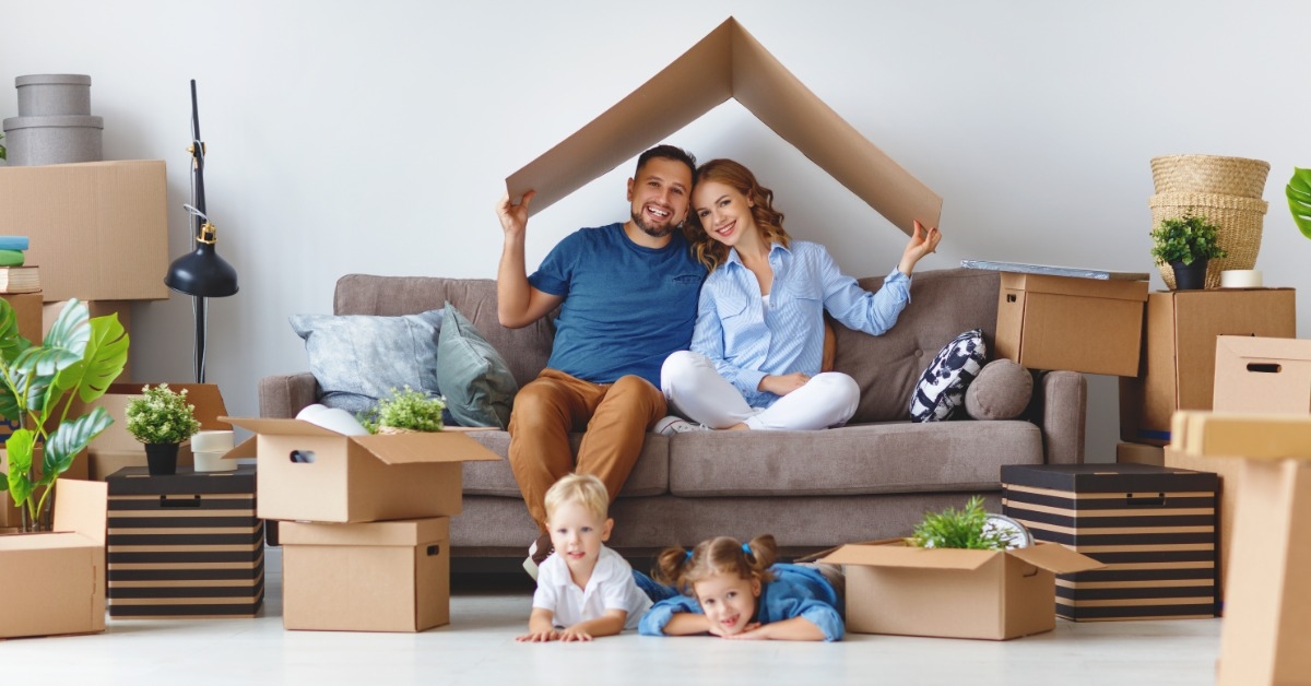 happy family sitting in couch with moving boxes 