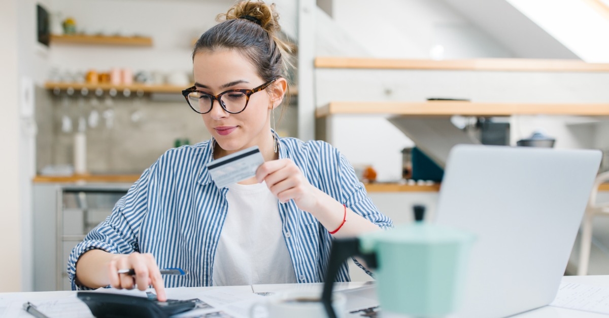 woman using calculator while holding a card