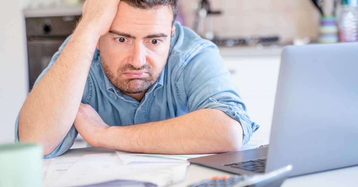 man staring at papers and calculator on table