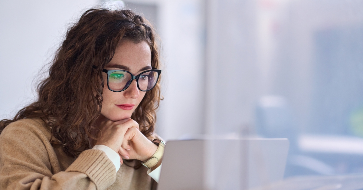 student wearing glasses using laptop watching online webinar