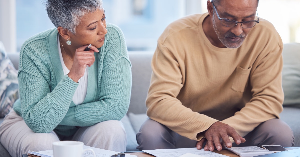 senior african american couple sitting on a couch looking at paperwork