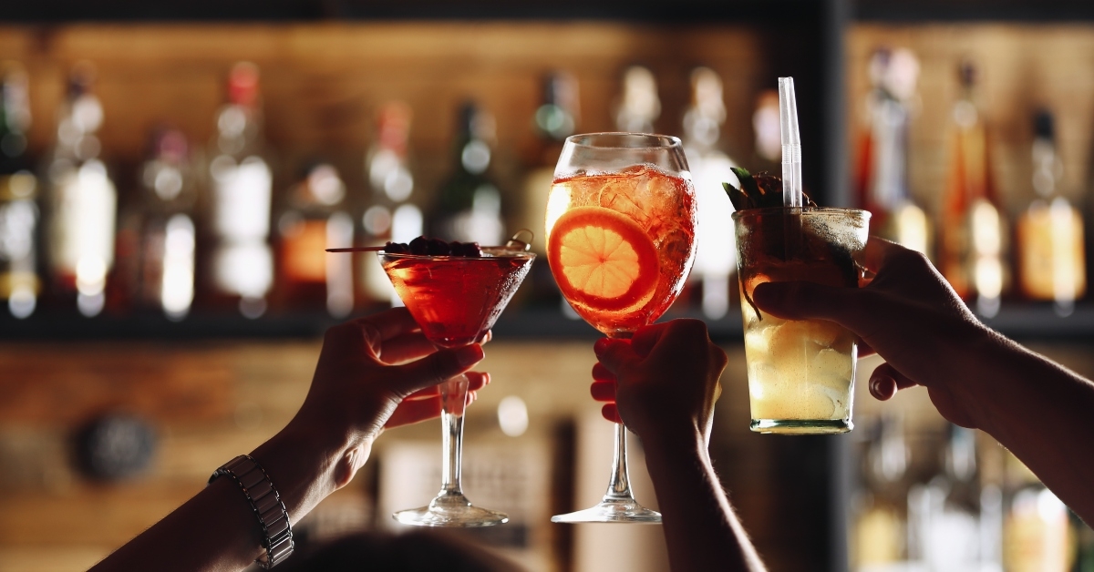 friends toasting with cocktails in bar