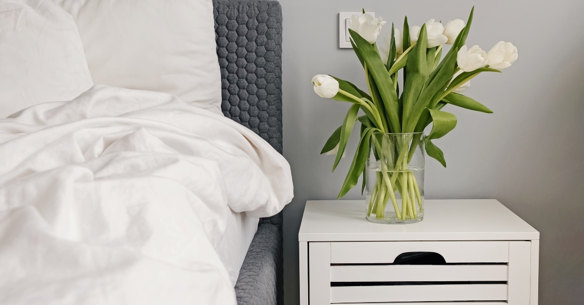 white tulips in a vase near the bed