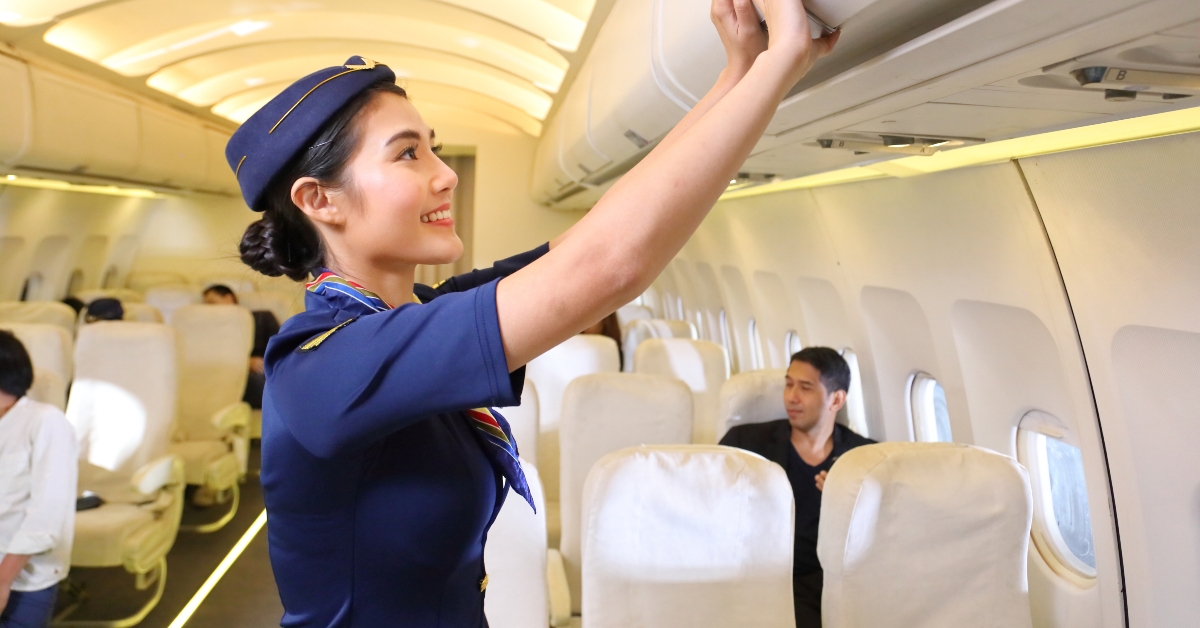 flight attendant closing the overhead luggage compartment lid