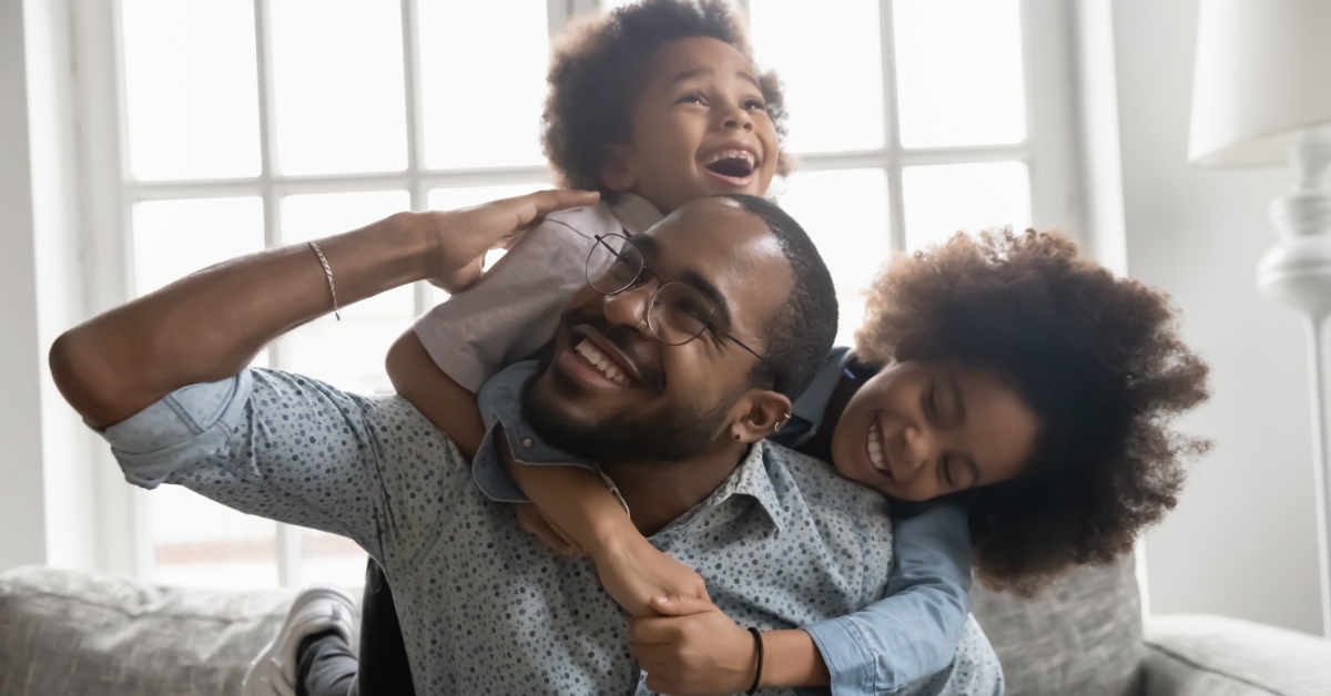 happy african man playing around with kids at home