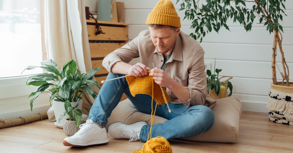 man knitting at home