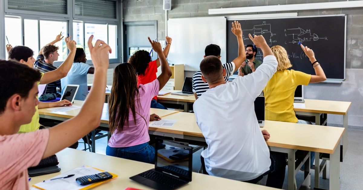 students in class raising hands to ask questions