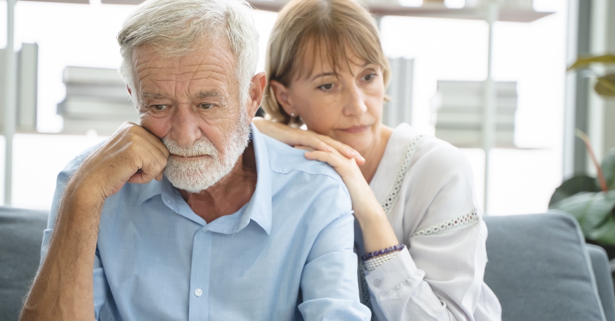 senior couple thinking while sitting on couch