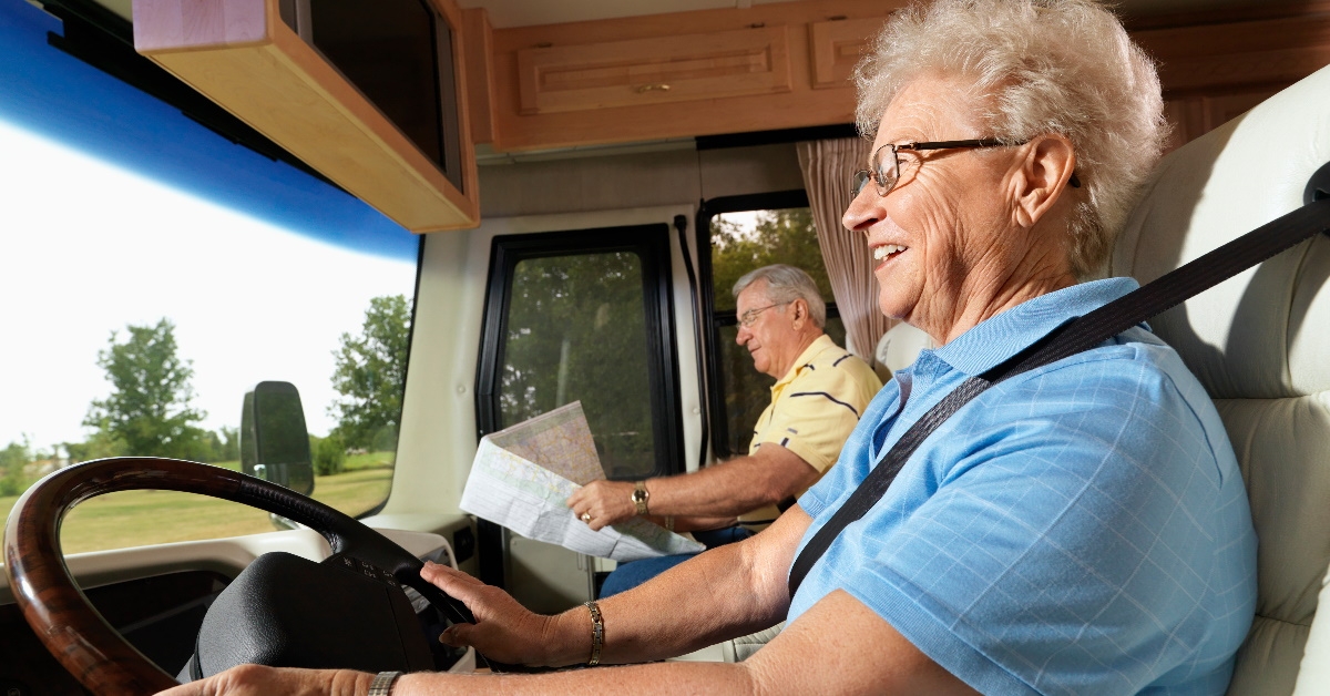 senior woman driving rv with senior man on passenger seat