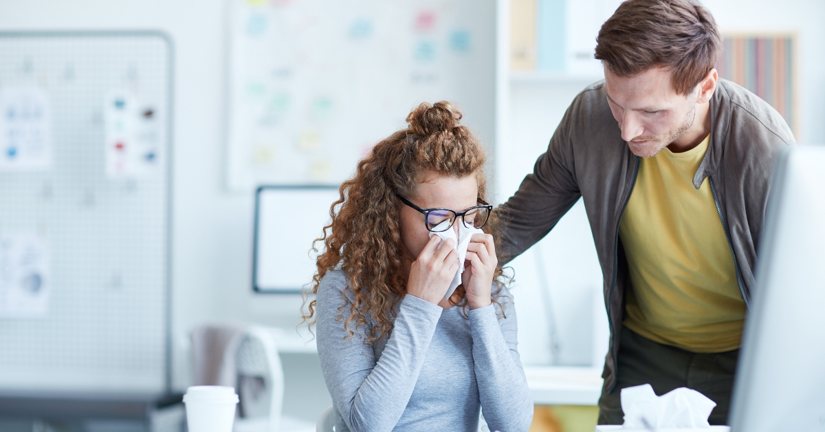 businessman leaning over his upset female crying colleague