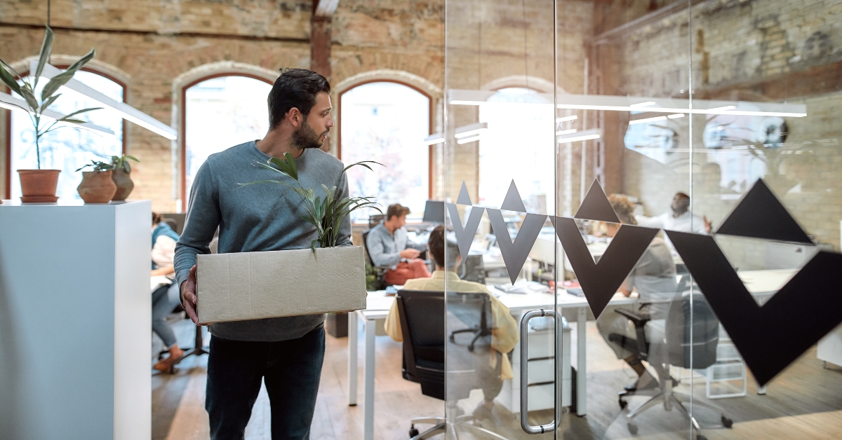 man holding box with personal things and leaving modern office